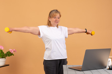 Fit woman doing home workout. Laptop computer with online gym training course. Happy fitness senior female watching exercise video. Personal trainer on the internet. Healthy diet program