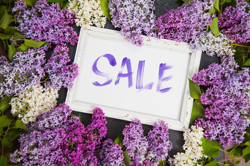 Spring shopping sale concept, handwritten word sale and lilac flowers on table. Floral arrangement...