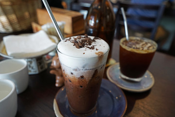 A glass of Iced black coffee and chocolate cacao with stainless steel straw