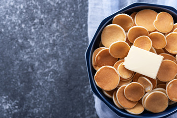 trendy cereal pancakes in blue bowl with buttering toast on blue gauze on grey background, copy space