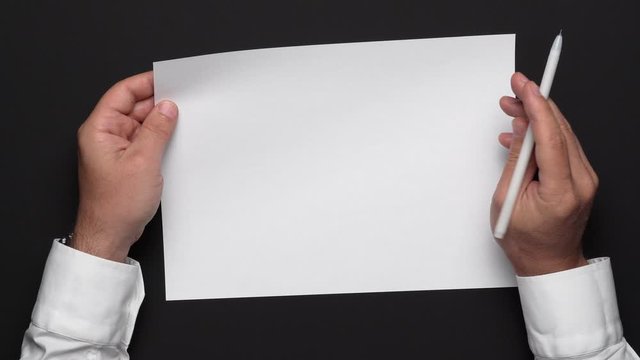 a blank sheet of paper and a businessman's hands on a black table, a white shirt and a wrist watch, a top view-a template for any text or inscription