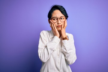 Young beautiful asian girl wearing casual shirt and glasses standing over purple background Tired hands covering face, depression and sadness, upset and irritated for problem