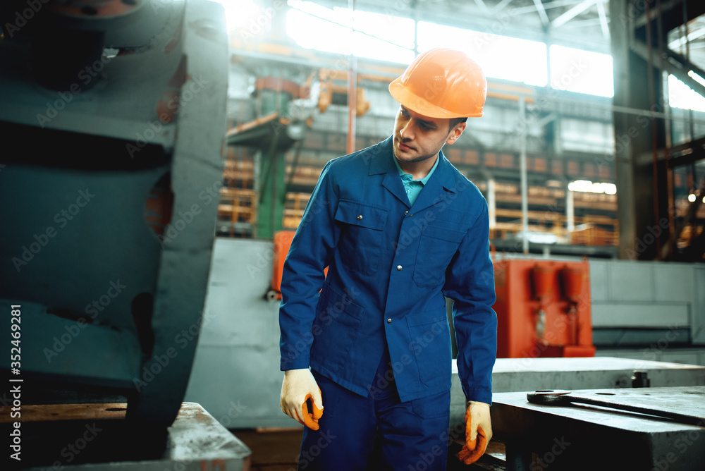 Wall mural Worker in uniform and helmet, metelworking factory