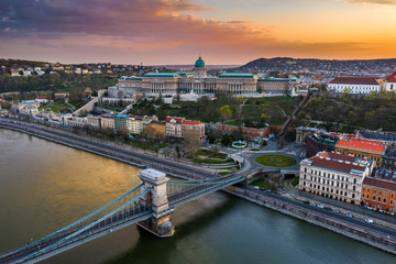 Fototapeta premium Budapest, Hungary - Aerial view of totally empty Szechenyi Chain Bridge with Clark Adam Square, Buda Castle Royal Palace and colorful sunset at background. Streets are empty due to 2020 Coronavirus