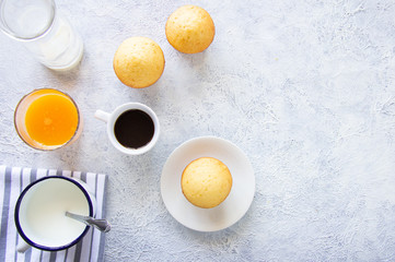 Breackfast with muffin, cup of coffe, cup of milk , orange juice on light background, top view