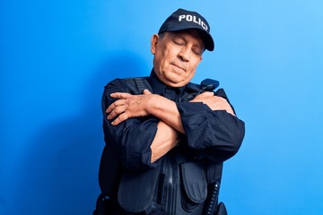 Senior man with grey hair wearing police uniform hugging oneself happy and positive, smiling...