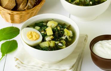 Green vegetable soup with sorrel leaves and eggs in a white bowl