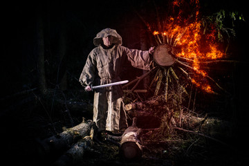 A monk in a cassock walks through the night forest with a sword and a lantern. Burning wood. Fiery sword. The magic monk.
