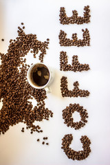 Cup of black coffee on white background with letter coffee wrote from fresh rosted beans. White cup of coffee and letters Coffee. Brown coffee letters isolated on a white background. Copy-space.