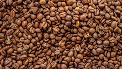 Fresh coffee beans brown seed texture background full wallpaper. Coffee beans roasted for the background. Mixture of different kinds of coffee beans. Close up.