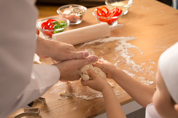 Close-up hands while cooking dough. Dad and son at home during isolation make pizza.