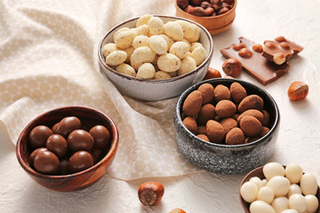 Different tasty chocolate nuts on white background