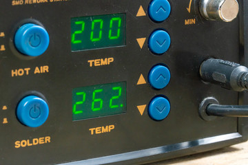Soldering station with led display, heating control controller, hot air gun and soldering iron. A man's hand sets up the soldering station.