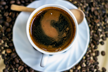 Top view of fresh black turkish coffee white cup. Coffee cup and beans isolated on a glass background. Turkish coffee and wooden spoon with roasted coffee beans.