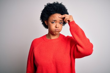 Fototapeta na wymiar Young beautiful African American afro woman with curly hair wearing red casual sweater worried and stressed about a problem with hand on forehead, nervous and anxious for crisis