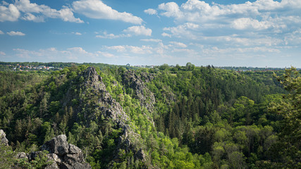 Fototapeta na wymiar Nature reserve Divoka Sarka (Wild Sarka) in Prague on a spring day. Blue sky, green trees and steep rocks in a valley seen from elevated viewpoint. Beautiful hidden place for relaxation in the city