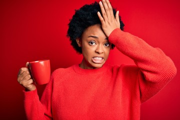 African American afro woman with curly hair drinking cup of coffee over red background stressed with hand on head, shocked with shame and surprise face, angry and frustrated. Fear and upset