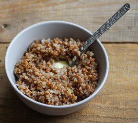 buckwheat porridge in a white bowl on a wooden table close up