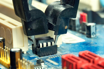 An engineer removes the programmable BIOS chip with the tongs from the motherboard. Firmware.