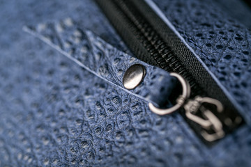 Zipper slider for a blue textured leather bag.