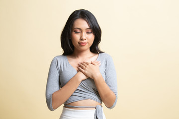 Obraz premium Faithful woman closes eyes and keeps hands on chest near heart, shows her kindness.