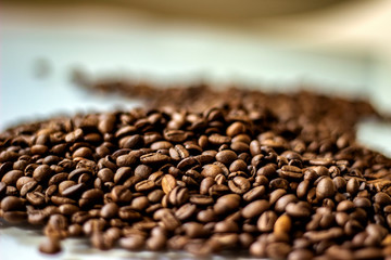 Falling roasted coffee beans isolated on white background.Close up of coffee beans.Beans isolated on white background top view.Grains of coffee. Brown coffee beans isolated on white board.Copy-space