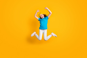 Full size photo of crazy little lady jump high good mood celebrate football team winning raise fists scream wear casual blue t-shirt headband trousers shoes isolated yellow color background