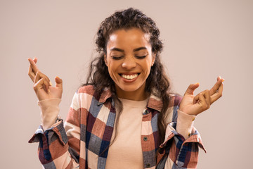 Studio shot portrait of beautiful happy african-american ethnicity woman with fingers crossed.