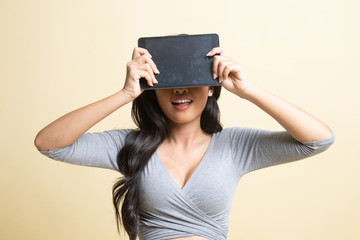 Young Asian woman with a computer tablet over her face.