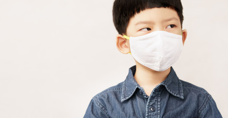 Banner, Cute little Asian boy wear medical face mask in daily life to protect himself from coronavirus during Covid-19 pandemic and social distancing. Stay safe & new normal for school student concept