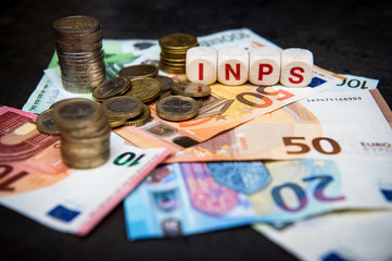 banknotes and coins of euro on a dark background and written INPS Italian pension institution