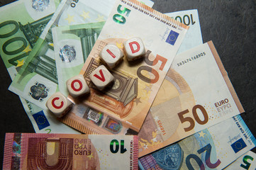 COVID euro banknotes on a dark background with written COVID view from top