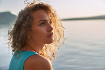 Portrait of serious pretty girl on background of lake.