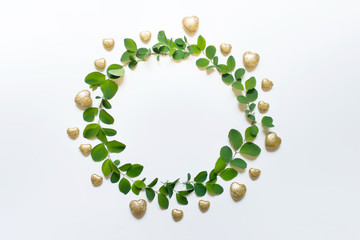 Circular wreath with green plant leaves and golden hearts. Photo with copy blank empty space.