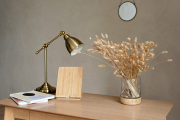 Natural wooden table in a modern style in beige tones with a vase of dried flowers and a copper...