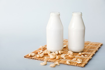 Bottles of tasty cashew milk on grey background