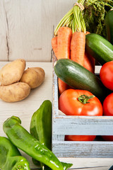 Fresh vegetables in wooden box on wooden background.