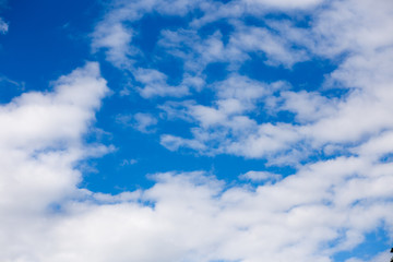 White fluffy clouds in blue sky in summer. Background with cloud
