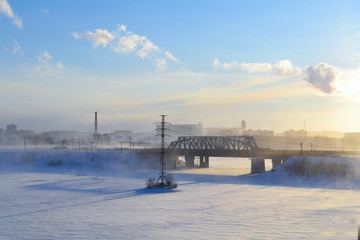 Winter railway bridge at sunset. The blue sky and the frozen river