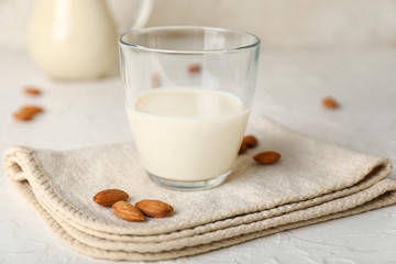 Glass of tasty almond milk on white background
