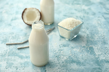 Bottle of tasty coconut milk on color background