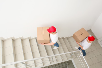 Loaders carrying boxes in the stairway
