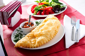 Cheburek - fried pie with meat and onions on a plate. Traditional dish of many turkic and mongolian peoples