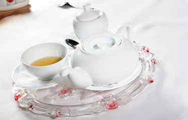 Pouring hot black tea from restaurant style cattle. Selective focused on kettle and poured tea.