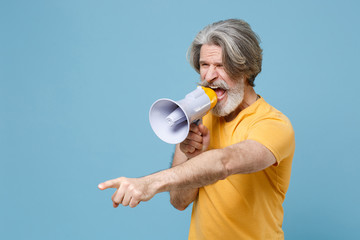 Angry elderly gray-haired mustache bearded man in casual yellow t-shirt posing isolated on blue...
