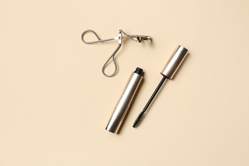 Mascara with eyelash curler on color background