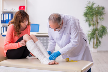 Young leg injured woman visiting old doctor traumatologist