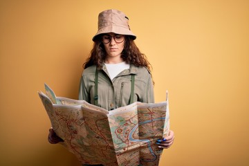 Beautiful tourist woman on vacation wearing explorer hat and water canteen holding city map with a confident expression on smart face thinking serious