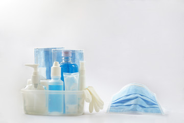 Blue face masks, alcohol, pump, saline bottle, gel, spray, tissue roll and gloves are in a clear box.  A shaped mask is by the set. The hygiene items are essential to prevent Corona virus (Covid-19).