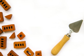 Small bricks and a trowel are scattered on a white background. Children's constructor. Background on the theme of construction.